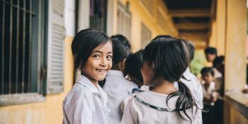 A schoolgirl turns and smiles as she walks in the corridor with her friends