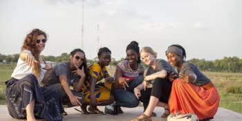 A team of female ICS volunteers crouch down and pose together