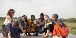 A team of female ICS volunteers crouch down and pose together