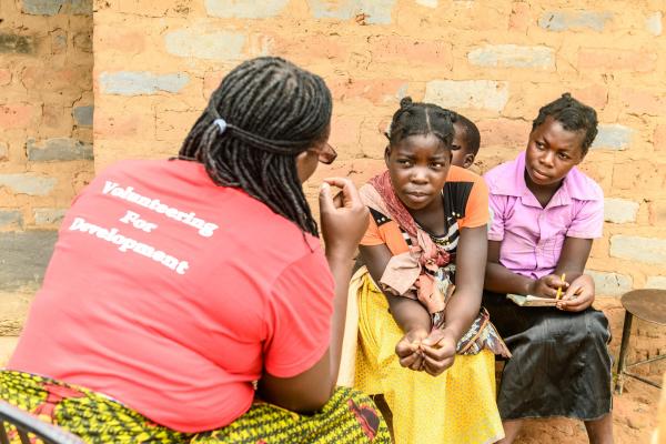 Volunteer Monica Atim talks to 16-year-old Mary and 14-year-old Veronica