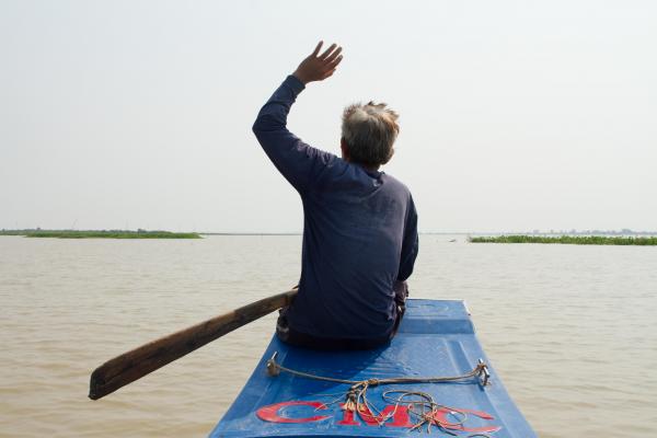 Pel Pon waves from his fishing boat on the Tonle Sap.