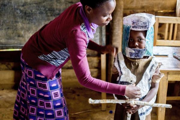 Teacher with child in moto costume made of rice sacks