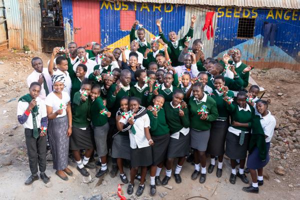 Volunteers Gladys and Susan with a group of schoolchildren holding woven paper stars